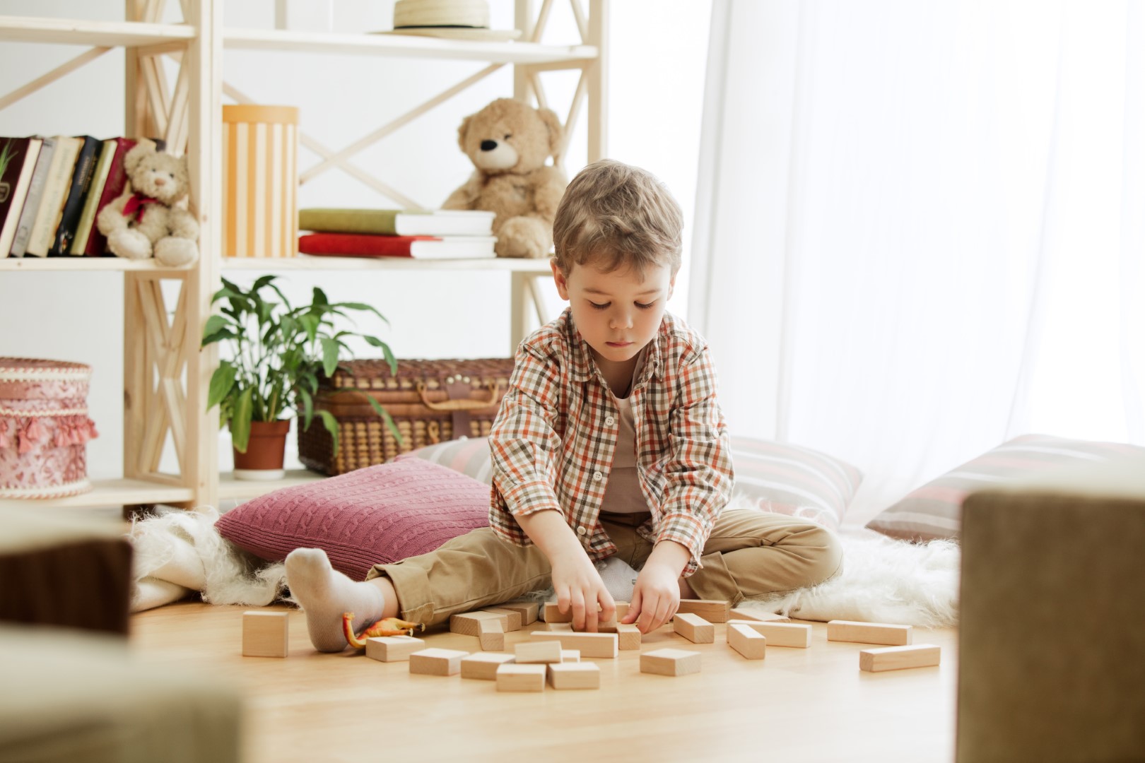 Little child sitting on the floor. Pretty boy palying with wooden cubes at home. Conceptual image with copy or negative space and mock-up for your text